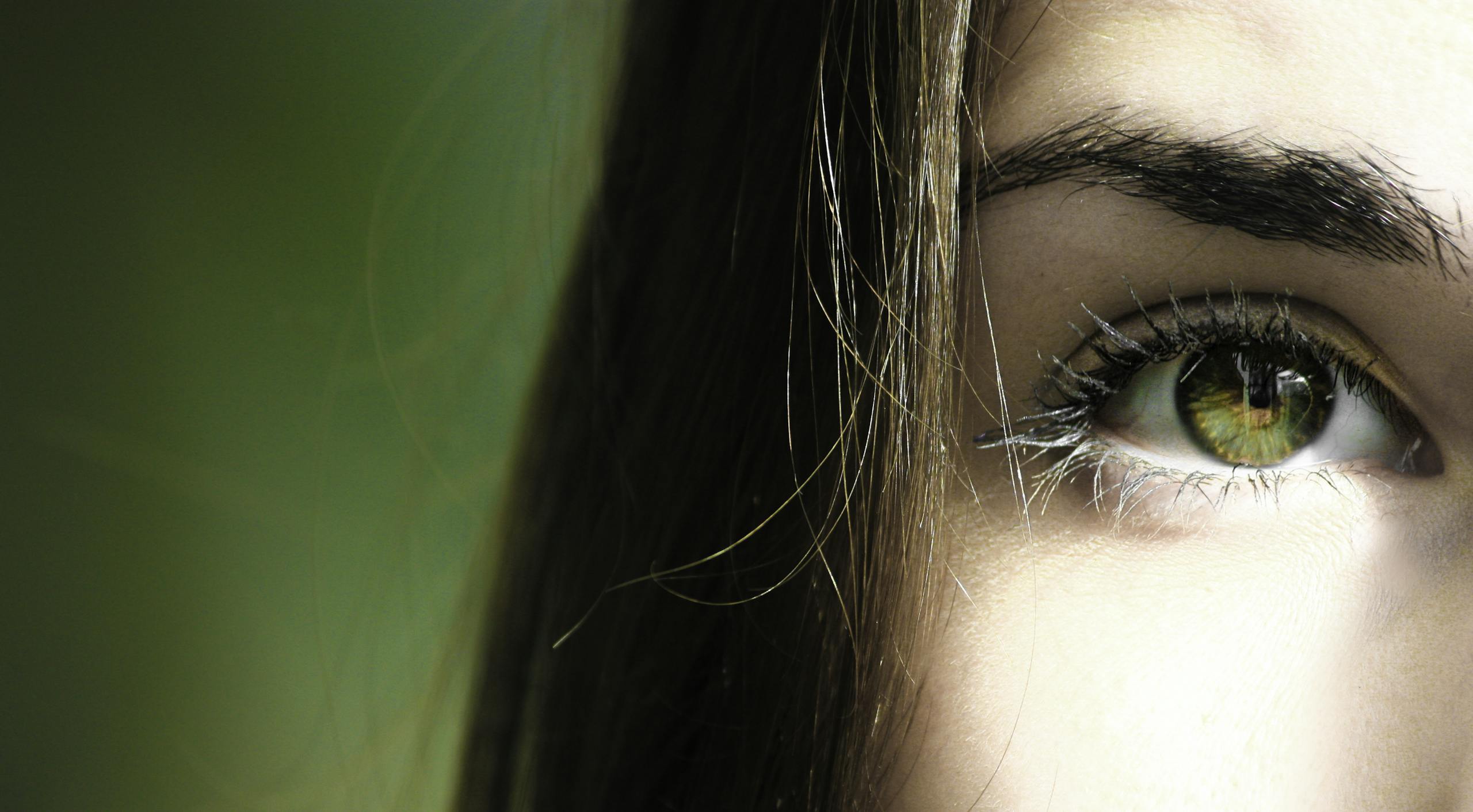 A detailed close-up of a woman's eye with green iris, capturing beauty detail.